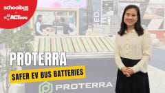Promotional graphic from School Bus Fleet at ACT Expo featuring a Proterra representative standing beside a battery display booth. Large text reads “Proterra” and “Safer EV Bus Batteries.” The background shows battery components and attendees at the ACT Expo trade show floor.