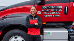 Photo of smiling truck driver Harold Perry with arms crossed in front of Southeastern Freight Lines truck