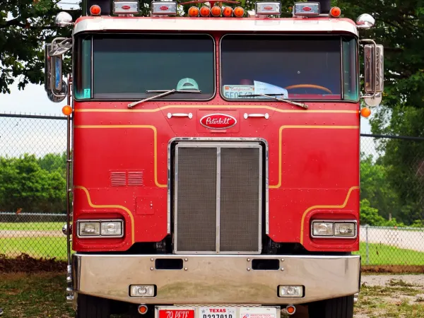 Red cabover heavy duty vintage truck parked on the grass