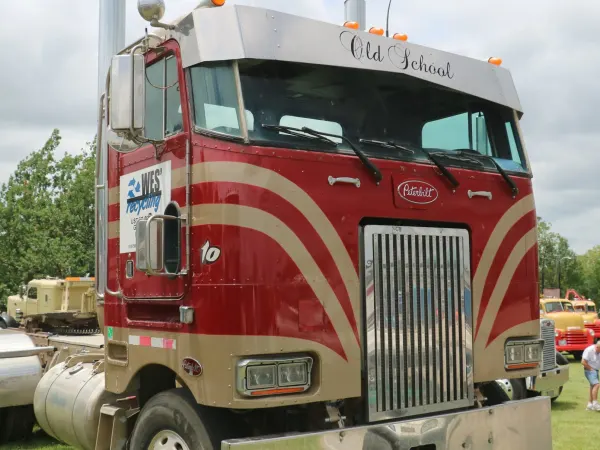 A red Peterbilt cabover daycab truck with tan stripes and chrome accessories