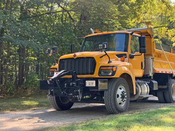 Yellow International HV truck on gravel road in the woods