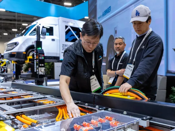 Man examining electric truck powertrain on display