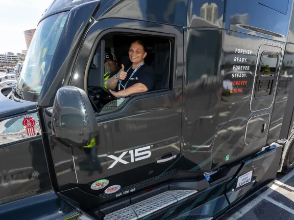 Truck driver giving a thumbs up behind the wheel of a heavy duty truck