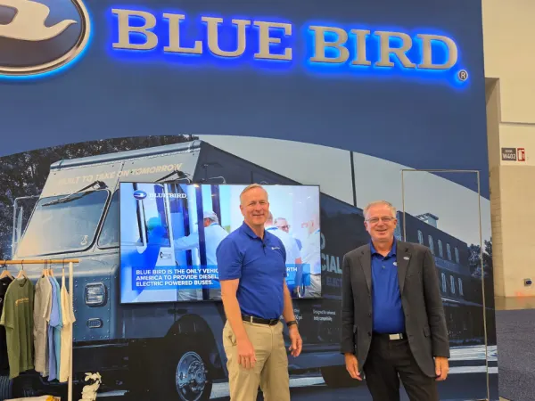 Blue Bird executives stand at the company’s ACT Expo booth showcasing alternative fuel and electric school bus solutions.