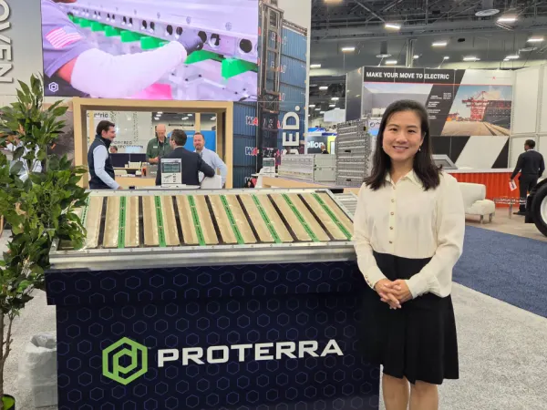 A Proterra representative stands beside the company’s commercial EV battery technology exhibit at ACT Expo 2026.