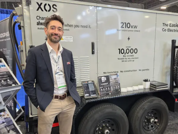 Xos representative Aldan Shank stands beside the company’s mobile charging solution designed for fleet electrification at ACT Expo 2026.