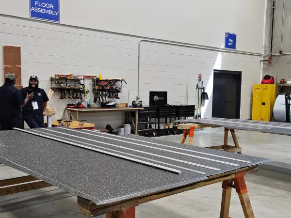 Wheelchair securement flooring panels assembled on worktables inside AMF Bruns manufacturing facility