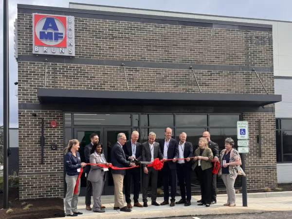 AMF Bruns executives stand outside a new company facility during a ribbon cutting ceremony.