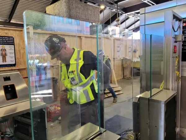 Construction crews installing glass doors on new faregates at Lindbergh Center Station.
