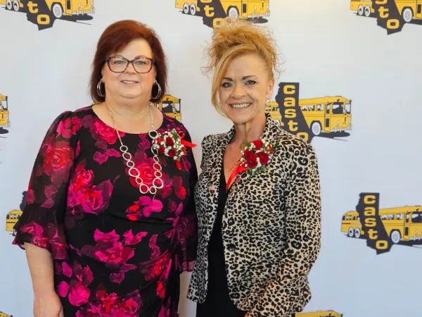 Two conference leaders pose for a portrait in front of a CASTO step-and-repeat backdrop featuring school bus logos.