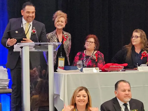 Award recipient smiles at a podium while holding a plaque during a formal recognition ceremony at the conference banquet.