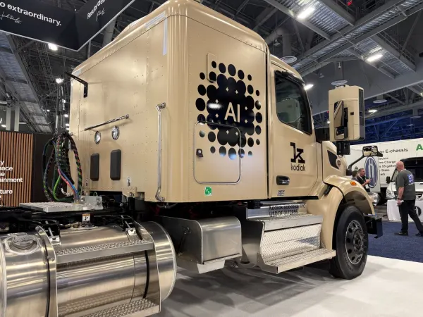 Khaki colored semi tractor on exhibit floor with "AI" graphic on the side