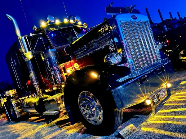 Dark colored Peterbilt vintage trucks with colorful accent lights at night