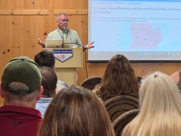 Bill Holcomb presents an interactive map showing electric school bus locations and charging stations across Michigan during a conference educational session.
