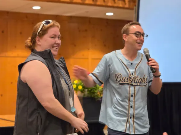 A BusRight representative announces the winner of the company's vacation giveaway while the winning attendee smiles beside him during the conference.