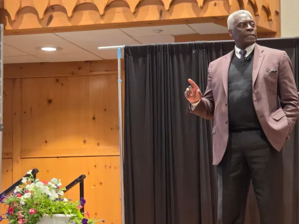 Keynote speaker Nathanial "Coach" Hearne stands on stage addressing attendees during the Michigan Association for Pupil Transportation conference at Boyne Mountain Resort.