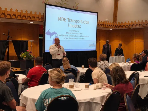 Michigan Department of Education transportation director Troy Hansbarger presents state transportation updates to a room filled with school transportation professionals.