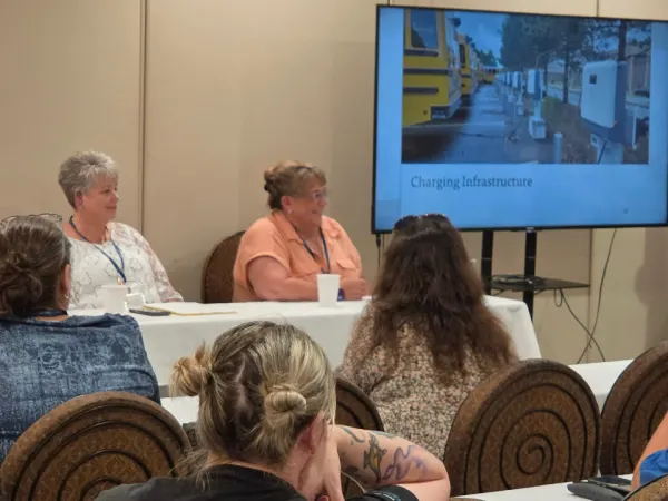 School transportation professionals participate in a panel discussion on alternative fuels while attendees listen to presentations about electric school bus charging infrastructure.