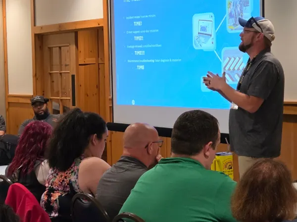 An Pro-Vision presenter leads a session on school bus video technology while attendees watch a presentation about camera systems and maintenance workflows.
