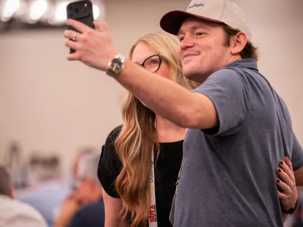 Two School Bus Fleet ConneX attendees smile while taking a selfie together during the event.