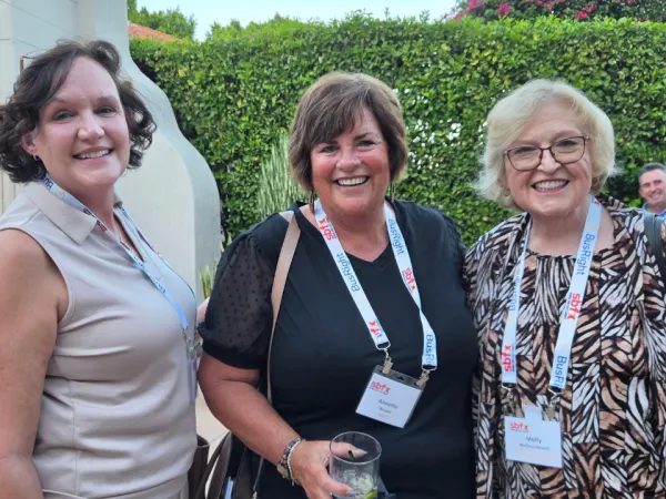 Three School Bus Fleet ConneX attendees smile for a photo during the outdoor welcome reception in Scottsdale, Arizona.