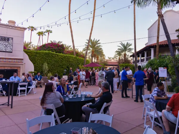 School Bus Fleet ConneX attendees network during an outdoor evening reception surrounded by palm trees at the Scottsdale resort.