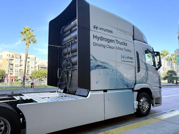 White Hyundai Xcient FCEV cabover outside convention center from side/rear view