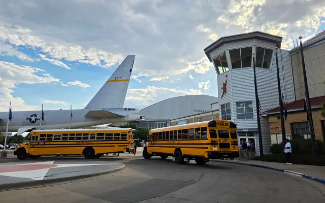 Two school buses parked in front of the Wings Over the Rockies Air & Space Museum in Denver.