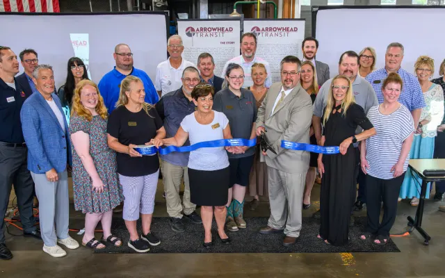 Business and community members pose during a ribbon cutting.