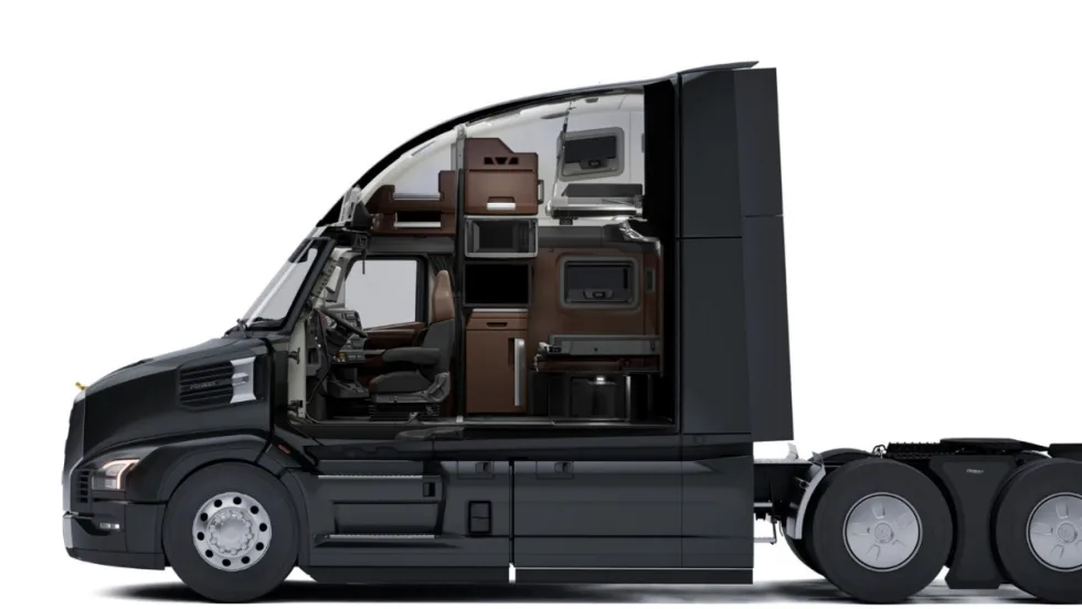 Side cutaway view of a Mack Pioneer truck cab showing the driver’s seat and sleeper area with storage cabinets, microwave, bunk beds, and workspace inside the cab interior.