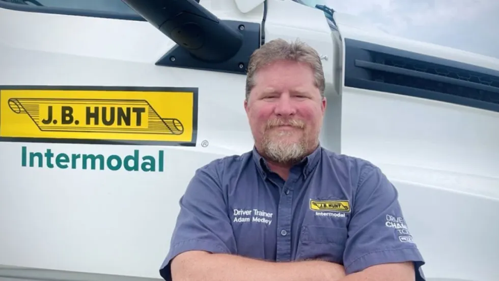 J.B. Hunt driver Adam Medley standing in front of his truck after being named the 2025 Goodyear Highway Hero.