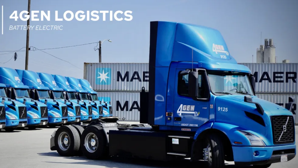 A row of blue Volvo VNR battery-electric trucks operated by 4GEN Logistics parked in front of Maersk shipping containers at a logistics yard.