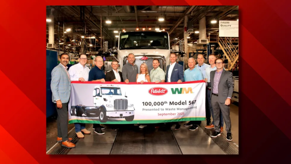 Peterbilt and WM representatives stand in front of the 100,000th Model 567 truck during a ceremony at Peterbilt’s Denton, Texas, manufacturing facility, holding a banner marking the milestone.