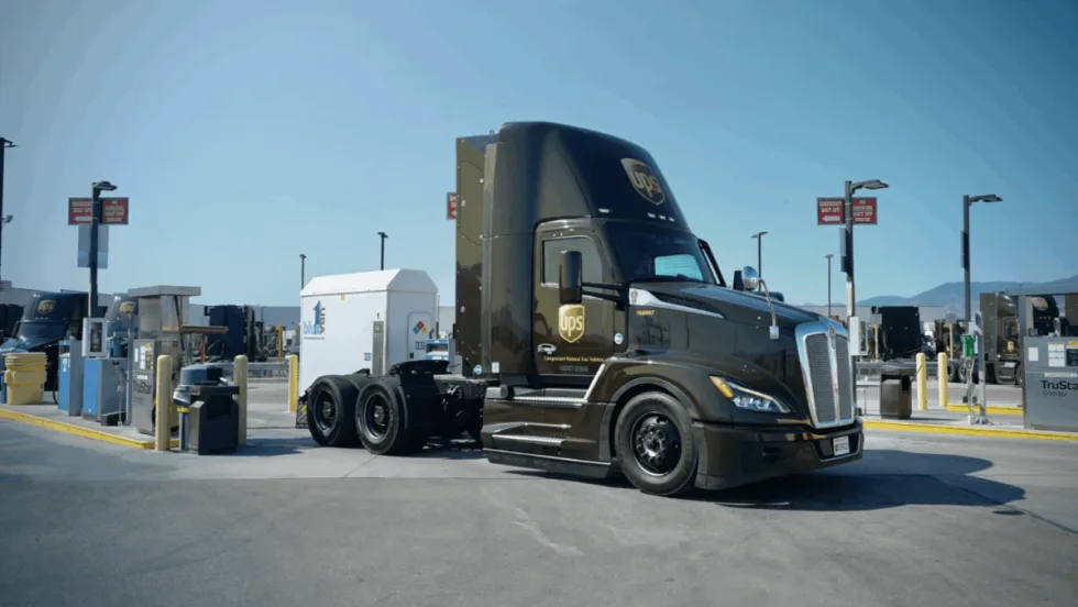 A UPS compressed natural gas (CNG) tractor is parked at a fueling station under clear skies, showcasing the company’s use of alternative fuel vehicles in its delivery fleet.