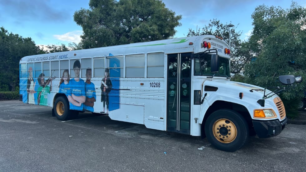 A Blue Bird Vision propane school bus operated by the Boys and Girls Club of Martin County, featuring exterior graphics of students and the slogan “Great Futures Start Here,” parked in a Florida lot.