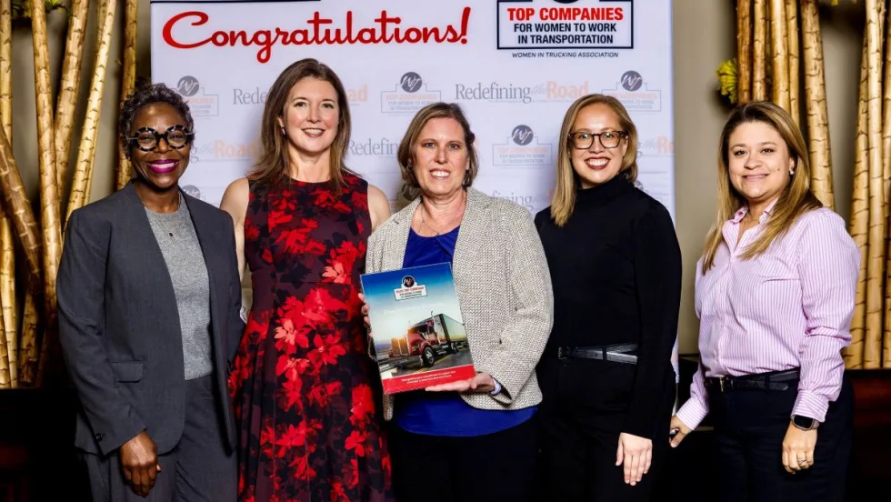 Five Peterbilt representatives pose with an award plaque after the company was named a 2025 Top Company for Women to Work in Transportation by the Women In Trucking Association.