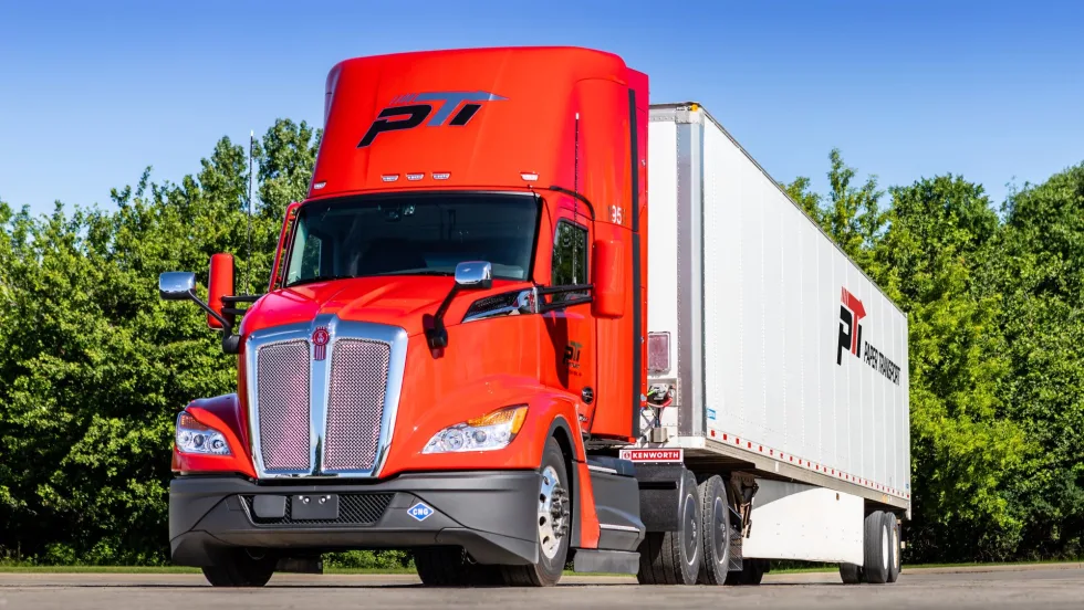 Red Kenworth truck pulling Paper Transport trailer