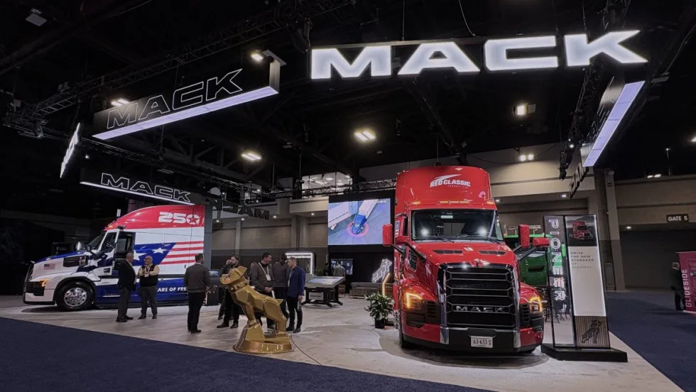 wide angle photo of trade show booth with big "Mack" sign above, red Mack truck in the foreground