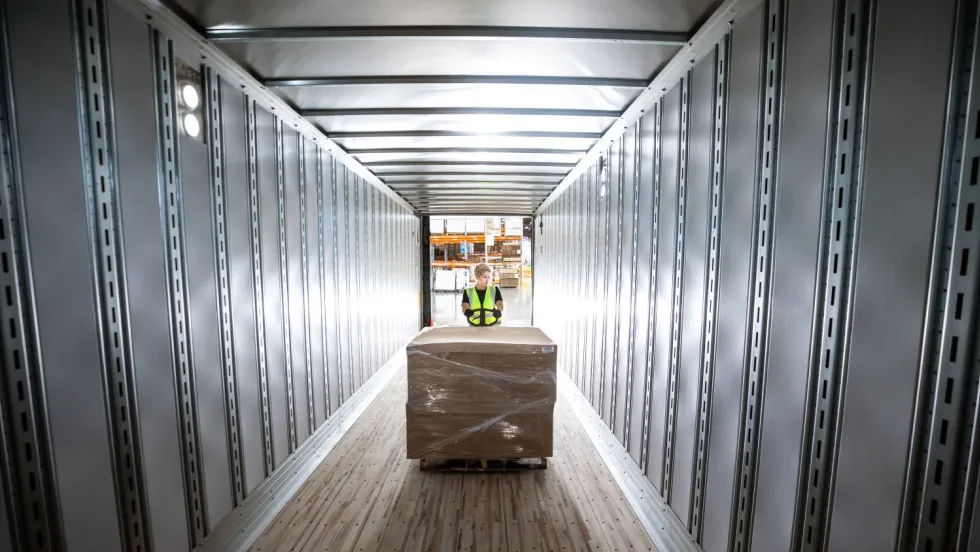 Empty trailer with worker loading a pallet of cargo