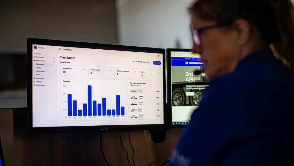 A monitor with a bar graph with a person sitting next to it wearing a headset.
