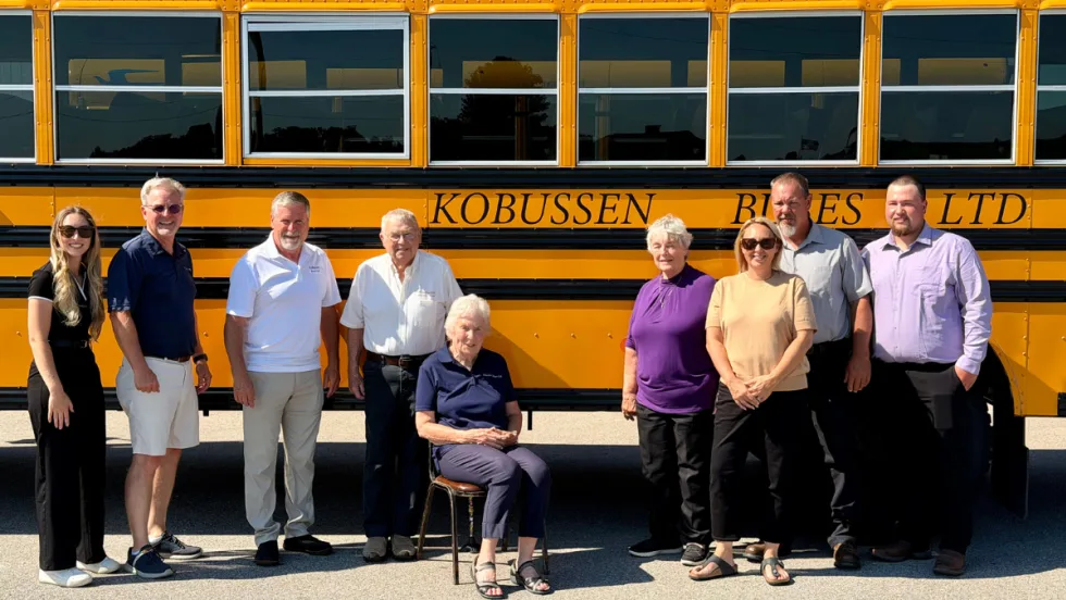 Multiple generations of the Kobussen family posing in front of a school bus.