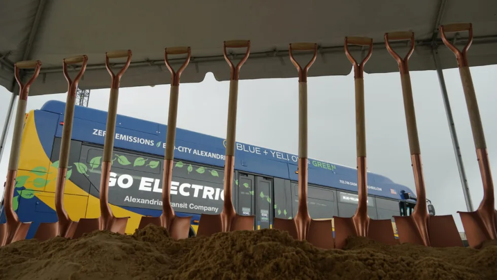 Shovels standing in dirt with a zero emissions bus in the background.