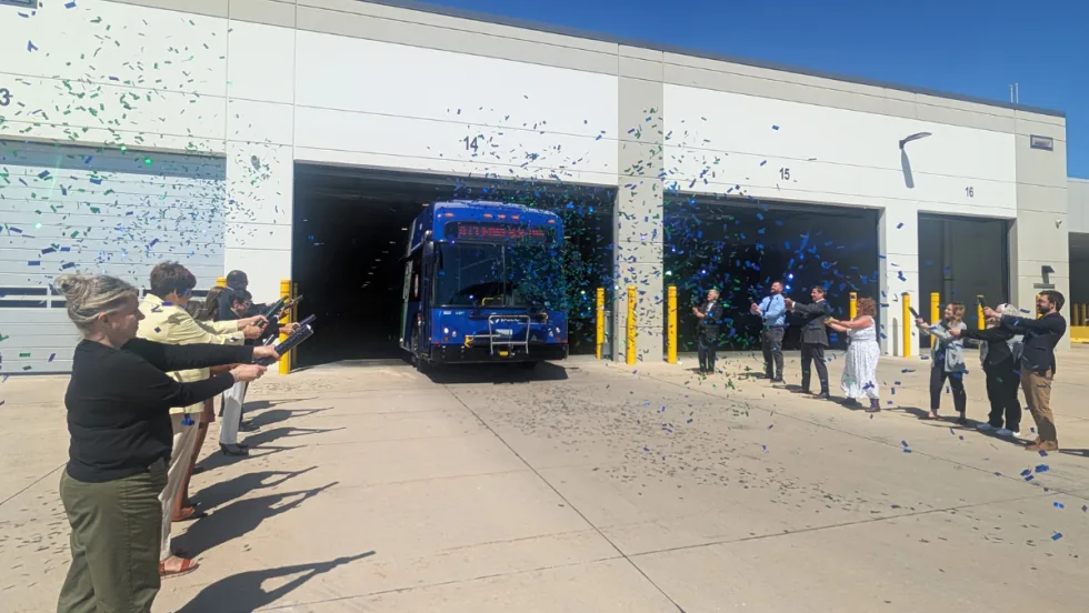 A group of people with confetti cannons and a Pace transit bus.