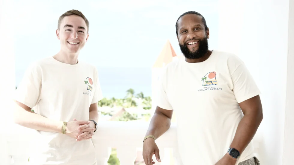 two men stand next to each other in white t-shirts