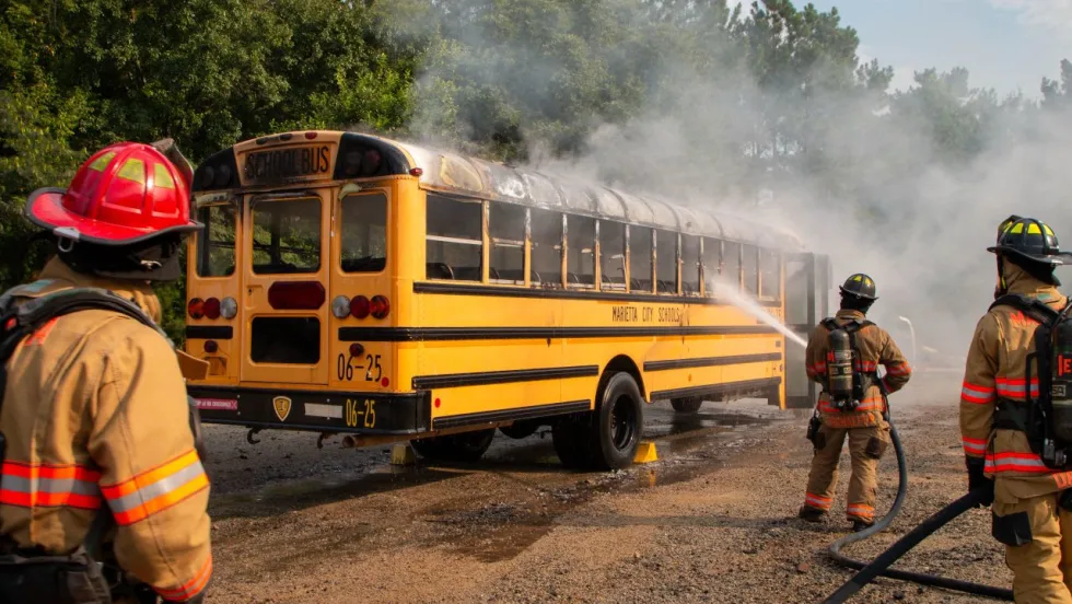 Firefighters spray water on a smoking Marietta City Schools school bus during a fire response drill.