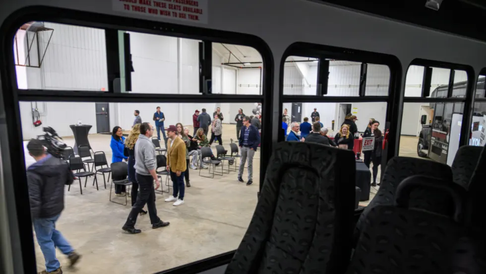 Perspective through the window of a transit bus into a warehouse event space for Arrowhead Transit.