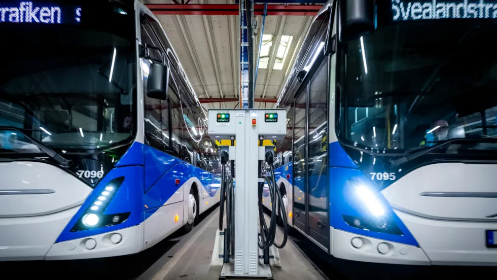 Two Swedish public transit buses next to a Hitachi Energy infrastructure.