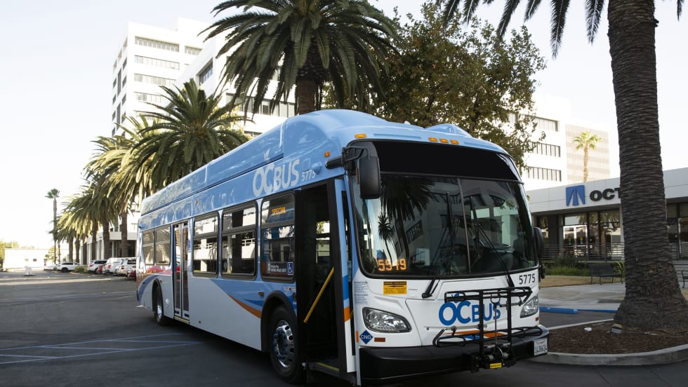 A blue and white OCTA public transit bus parked in the street.