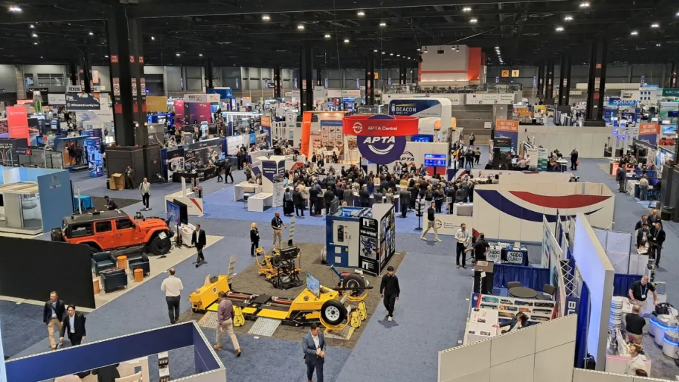 Overhead view of the APTA 2026 EXPO show floor at McCormick Place in Chicago, with attendees walking among exhibitor booths and gathering around APTA Central.