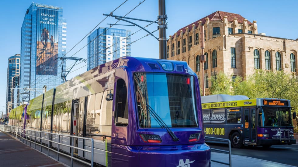 A Valley Metro light rail train and bus travel alongside each other in downtown Phoenix.